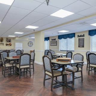 A bright and inviting dining area with several tables and chairs, featuring large windows and soft interior lighting.