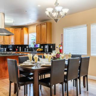 A modern open-concept dining area connected to a kitchen, featuring a stylish chandelier and elegant table settings.