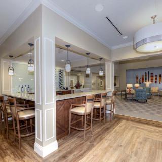 A modern kitchen with a bar area featuring seating and pendant lighting, showcasing contemporary design elements and wood flooring.