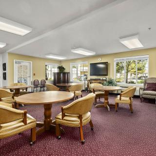 A spacious lounge area with tables, chairs, and a television.