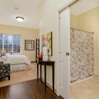 A cozy bedroom with elegant decor, featuring artwork and a soft carpet.