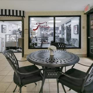 A cozy cafe interior with a round table and chairs, situated near a window showcasing the kitchen area.