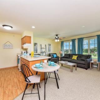 A modern open-concept living space with a kitchen, dining area, and bright natural lighting.