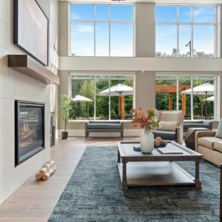 A modern living room with large windows, featuring a cozy seating area and a fireplace.