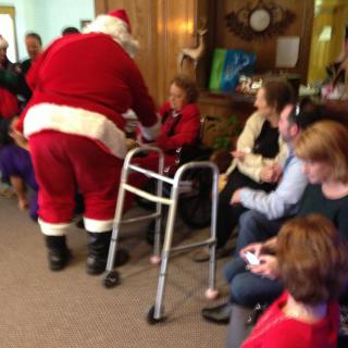 A festive Christmas event at a nursing home featuring Santa Claus interacting with residents.