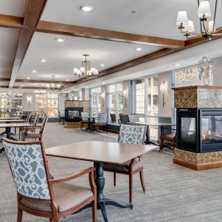 A modern dining area with elegant tables, chairs, and a central fireplace.