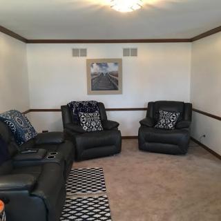 A cozy living room with black leather furniture and a decorative rug.