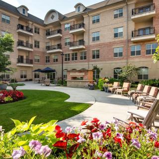 A beautiful apartment complex with a landscaped courtyard featuring vibrant flowers and outdoor seating.