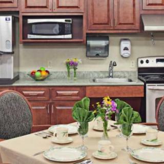 A cozy kitchen setup with a dining table set for four, including neatly arranged plates and cutlery.