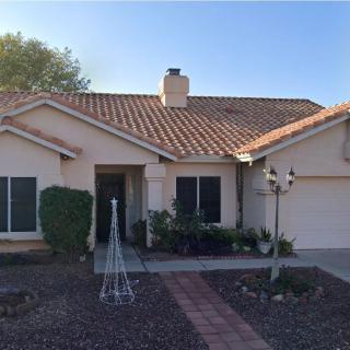 A single-story house with a tile roof and a small front yard on a sunny day.