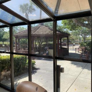 A view from inside a sunlit enclosure overlooking a gazebo and landscaped area.
