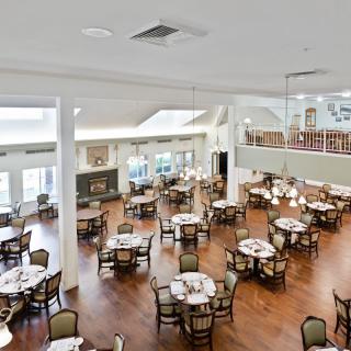 Spacious dining hall with wooden floors and neatly arranged tables.