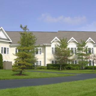 A suburban residential building with a well-maintained lawn and trees.