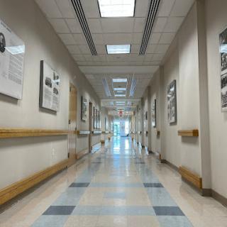 A spacious and well-lit hospital hallway, adorned with artwork on the walls.