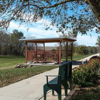 A peaceful park scene with a bench and gazebo along a tree-lined path.