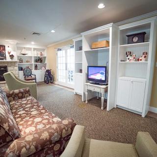 Cozy living room with floral sofa, built-in bookshelves, and a small television.