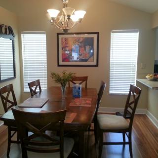 A cozy dining room with a wooden table, chairs, and a chandelier above.