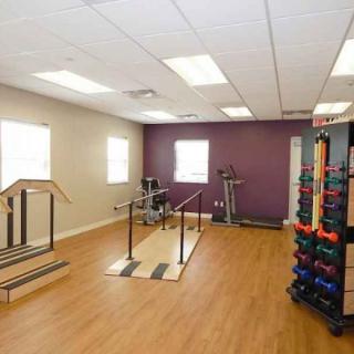 A well-equipped gym featuring exercise equipment and a colorful set of dumbbells.