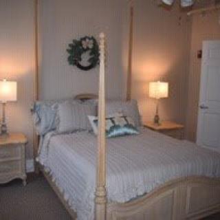 A cozy bedroom with a neatly made bed, flanked by two lamps on bedside tables.
