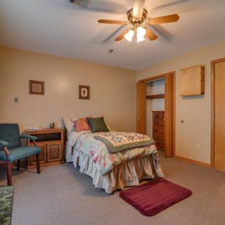 A cozy bedroom with a single bed, ceiling fan, and carpeted floor.