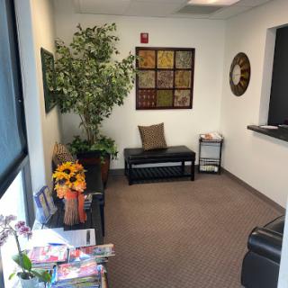 A cozy waiting room featuring a seating area, decorative plants, and wall art.