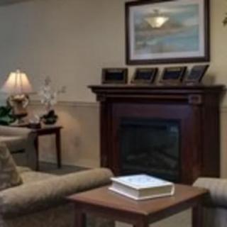 A cozy living room with a fireplace, comfortable seating, and a decorative painting.