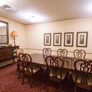 A classic dining room with a wooden table, chairs, and framed artwork on the walls.