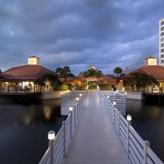 A scenic view of a bridge leading to buildings over water under a cloudy evening sky.