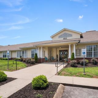 A single-story building with a welcoming entrance, surrounded by neatly landscaped grounds under a clear blue sky.