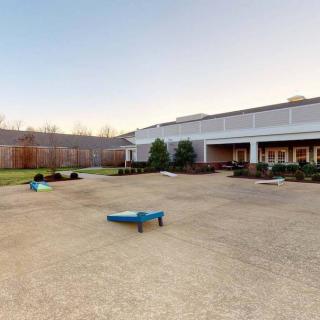 A spacious outdoor playground adjacent to a building, featuring play equipment and surrounded by a wooden fence.