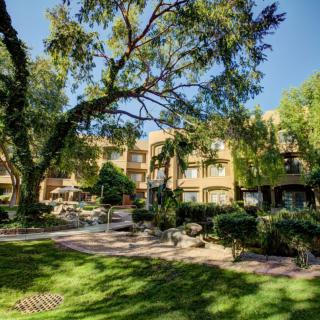 A sunny day view of a building surrounded by lush greenery and trees.