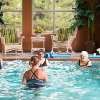 A group of people participating in a water aerobics class in an indoor swimming pool.
