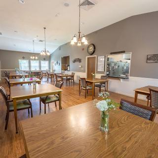 Spacious dining area with wooden tables and chairs, illuminated by elegant light fixtures.