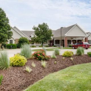 A beautifully landscaped garden with a building and driveway in the background.