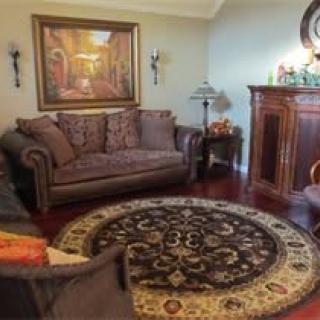 A cozy living room with a sofa, armchair, and a circular carpet in front of a fireplace.
