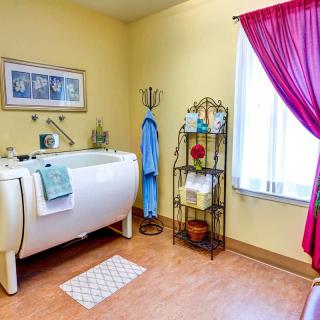 A cozy bathroom with a vintage bathtub, colorful towel rack, and bright curtains.