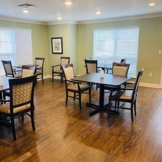 A well-lit dining area with multiple tables and chairs on a hardwood floor.