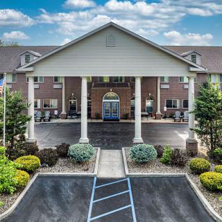 A well-maintained hotel entrance with a landscaped garden and clear sky.