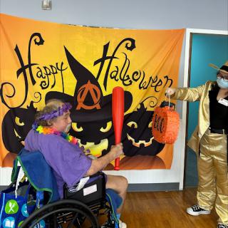 A festive Halloween celebration with decorations and costumes, featuring a participant in a wheelchair.