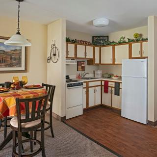 A cozy apartment kitchen with a dining table set for a meal, featuring a refrigerator and stylish interior decor.