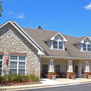 A residential building with stone facade and pitched roof under a clear blue sky.