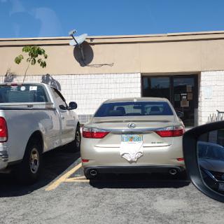 A view of two parked cars outside a building on a sunny day.