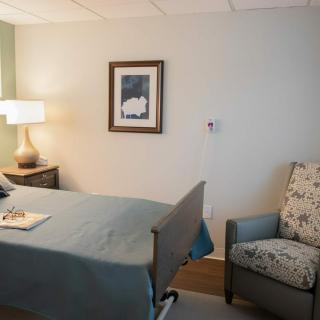 A hospital room with a bed, chair, and lamp.