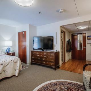 A cozy and well-furnished bedroom featuring a television, decorative carpet, and warm lighting.