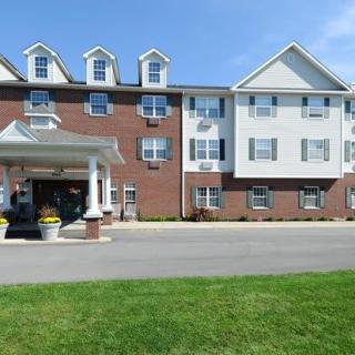 A multi-story residential building with a landscaped lawn and covered entrance.
