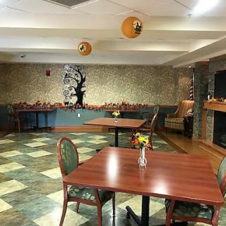 A cozy dining area featuring wooden tables and chairs, decorated with wall art and hanging ornaments.