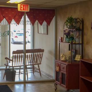A cozy waiting area with a rocking chair and decorative items near a glass exit door.