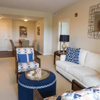 A cozy living room with a white sofa, patterned armchair, and blue accents.