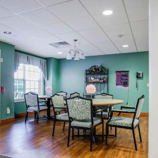 A cozy dining room with a round table and patterned chairs set against green walls.