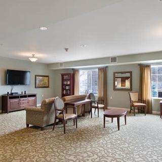 A spacious living room with comfortable seating and a television, featuring large windows and elegant decor.